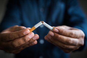 Black man breaking a cigarette in half