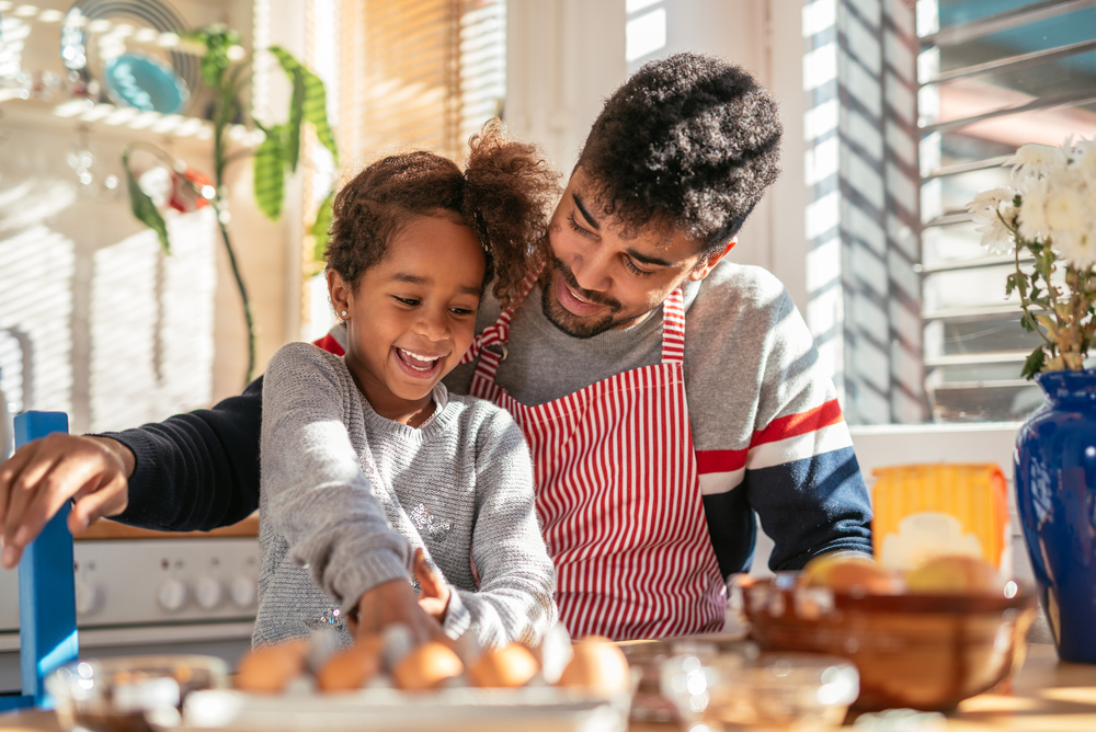 A father and his child cooking in the kitchen.