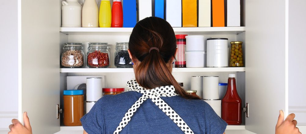 Woman seen from behind opening a food cupboard.